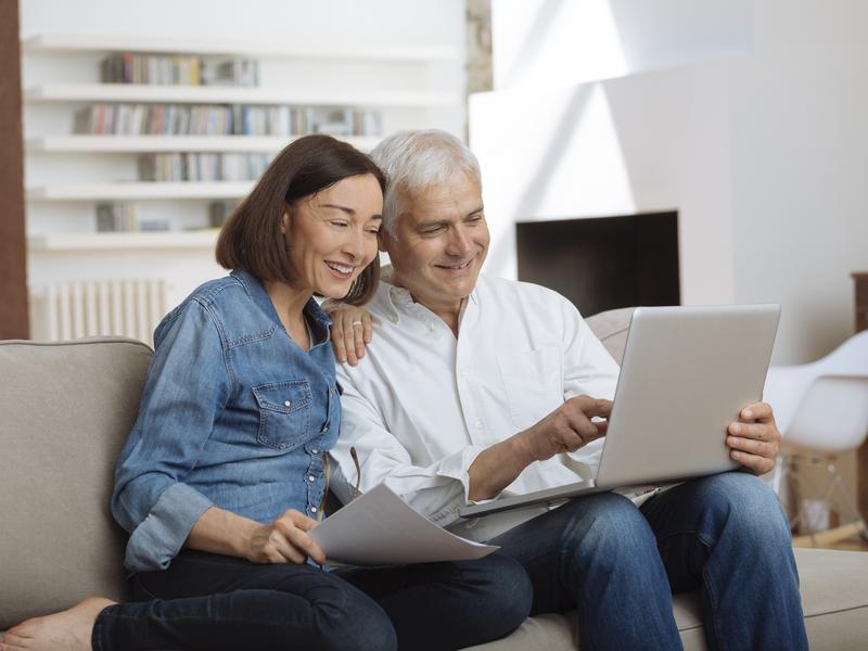 An expat couple reviewing their finances together at home on a laptop